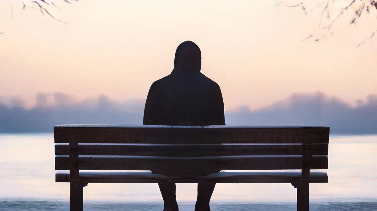 Person sitting on a bench in the winter, in contemplative reflection during the spiritual silent retreat.