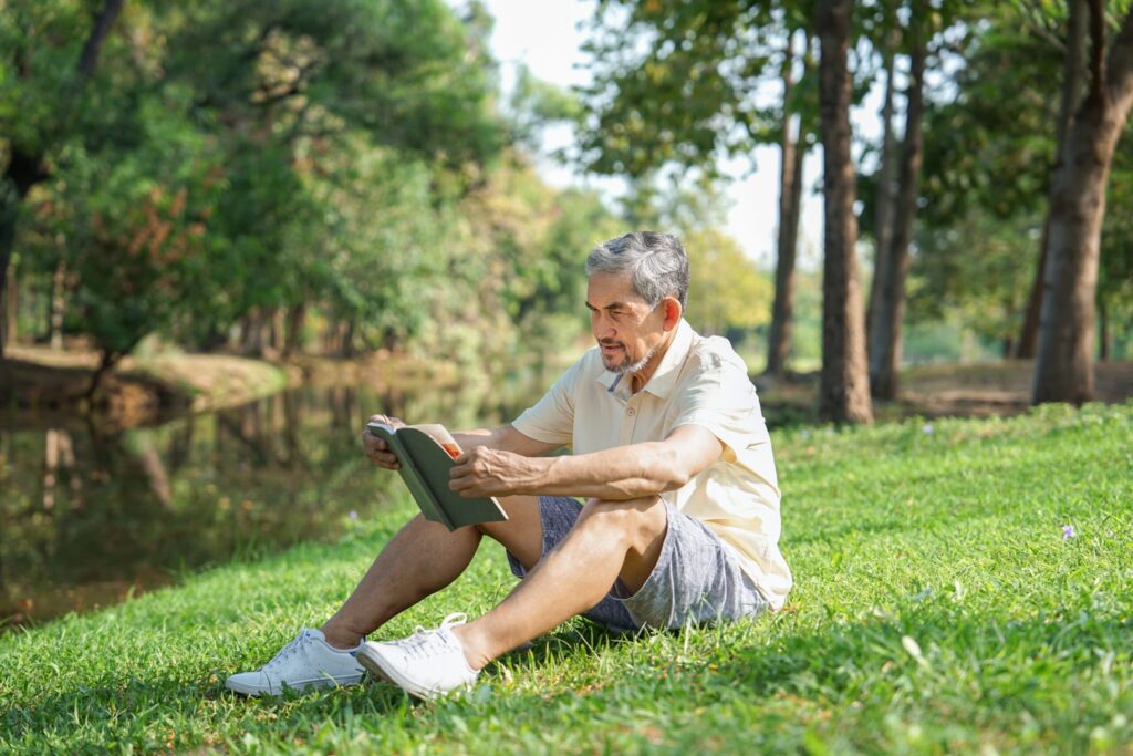 Man sitting on a grassy hill reading a book